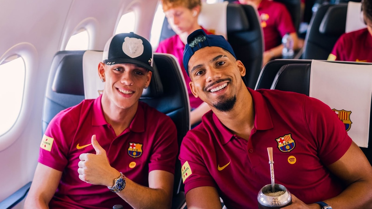 Two Barcelona players smile together during the flight to England