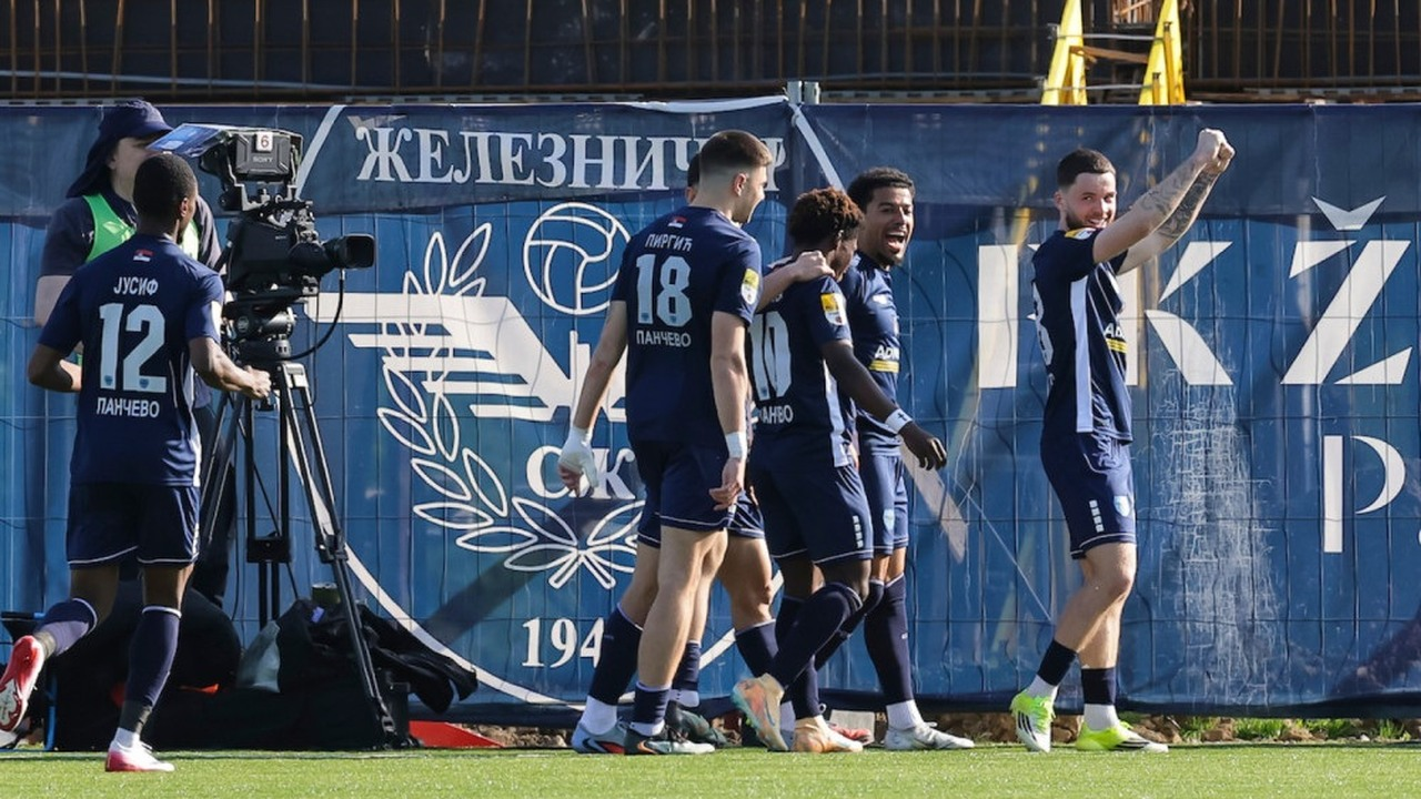 Zeleznicar Pancevo players celebrate together beside a club flag