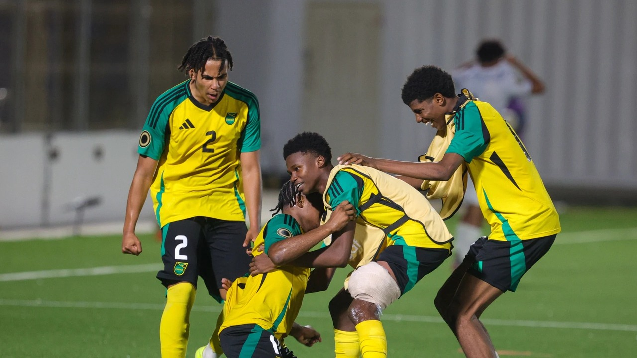 Jamaica under-20 players gather around a teammate on the pitch