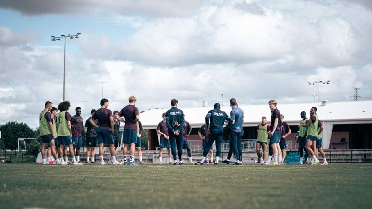 Brisbane Roar players and staff gather on a training field