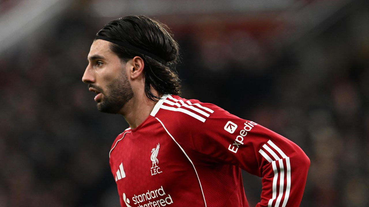 Dominik Szoboszlai stands on the pitch in Liverpool's red home kit