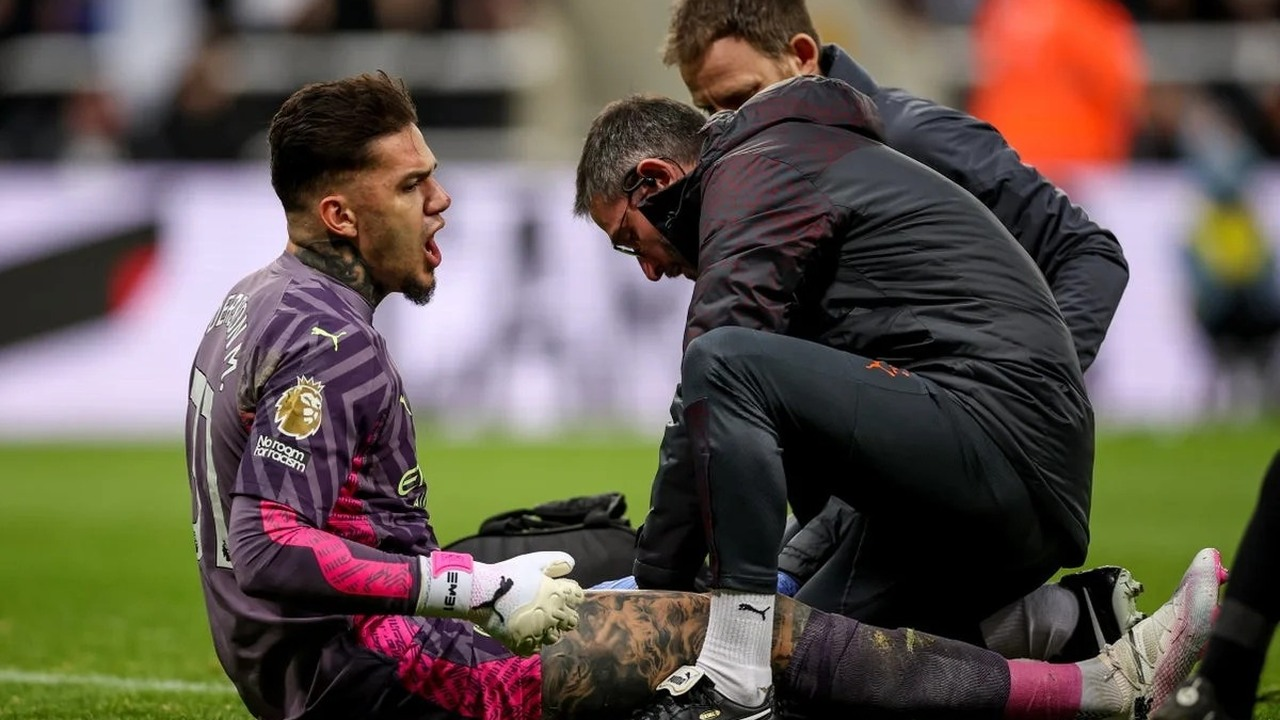 Medical staff check an injured goalkeeper inside the penalty area