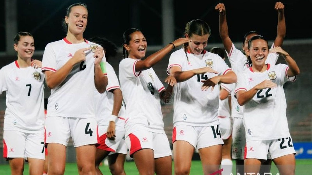 Indonesia women footballers celebrate together in white shirts