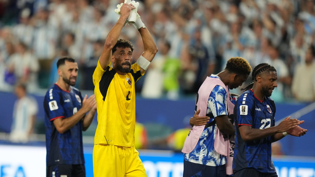 Vozinha raises his gloved hands above his head beside Cape Verde teammates