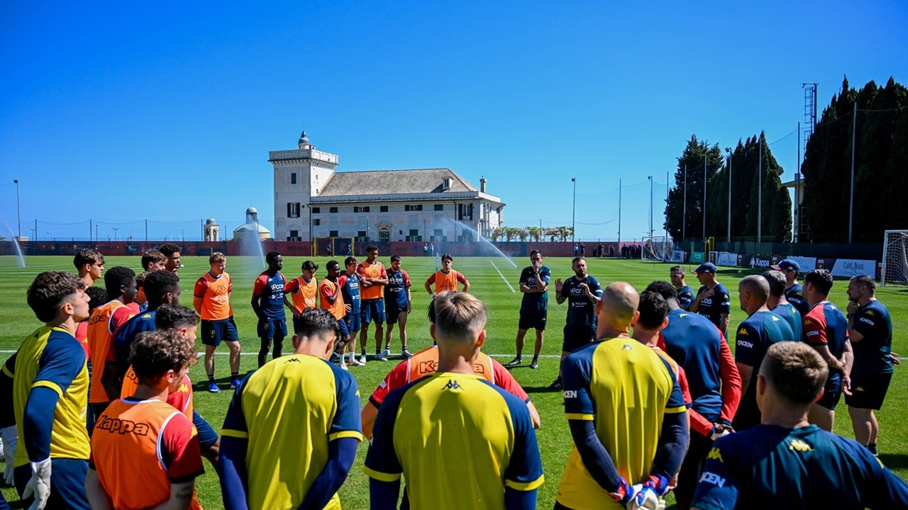 Genoa players and coaches gather on their training pitch