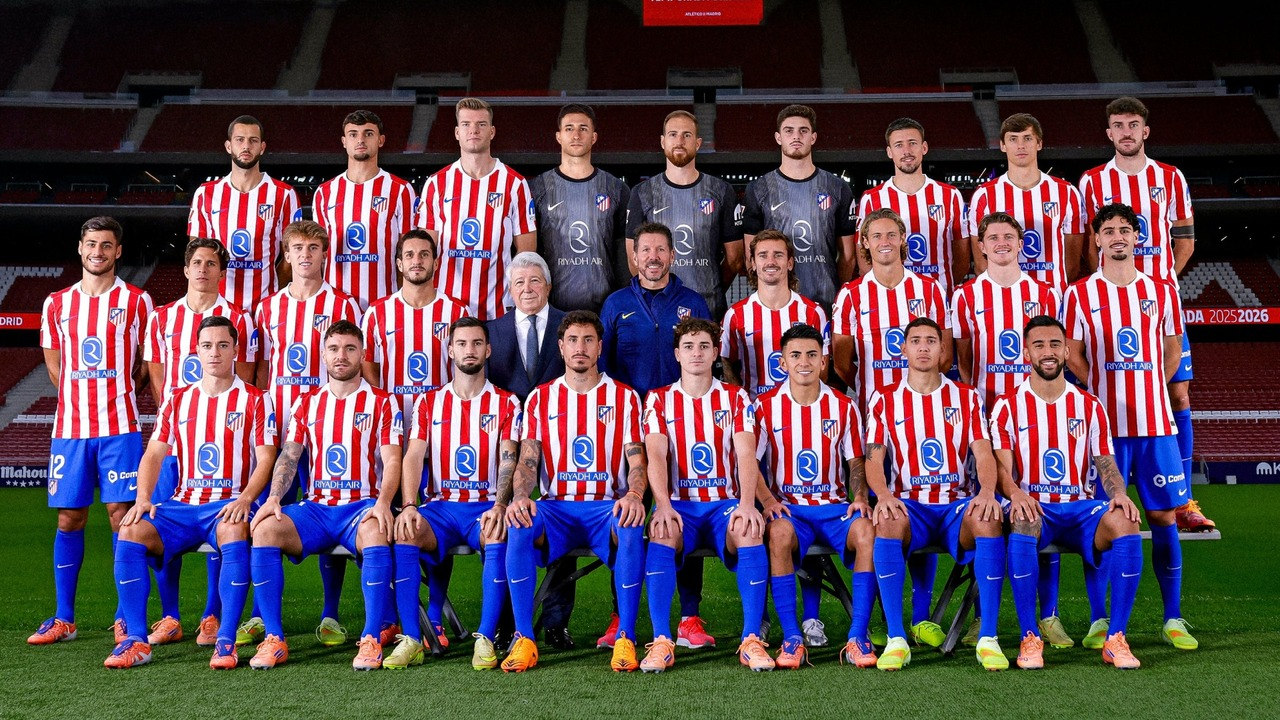Atletico Madrid players and staff pose together on the pitch