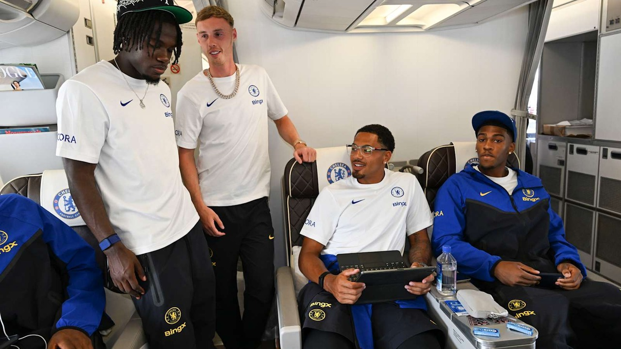 Four Chelsea players sit and stand together on an aircraft